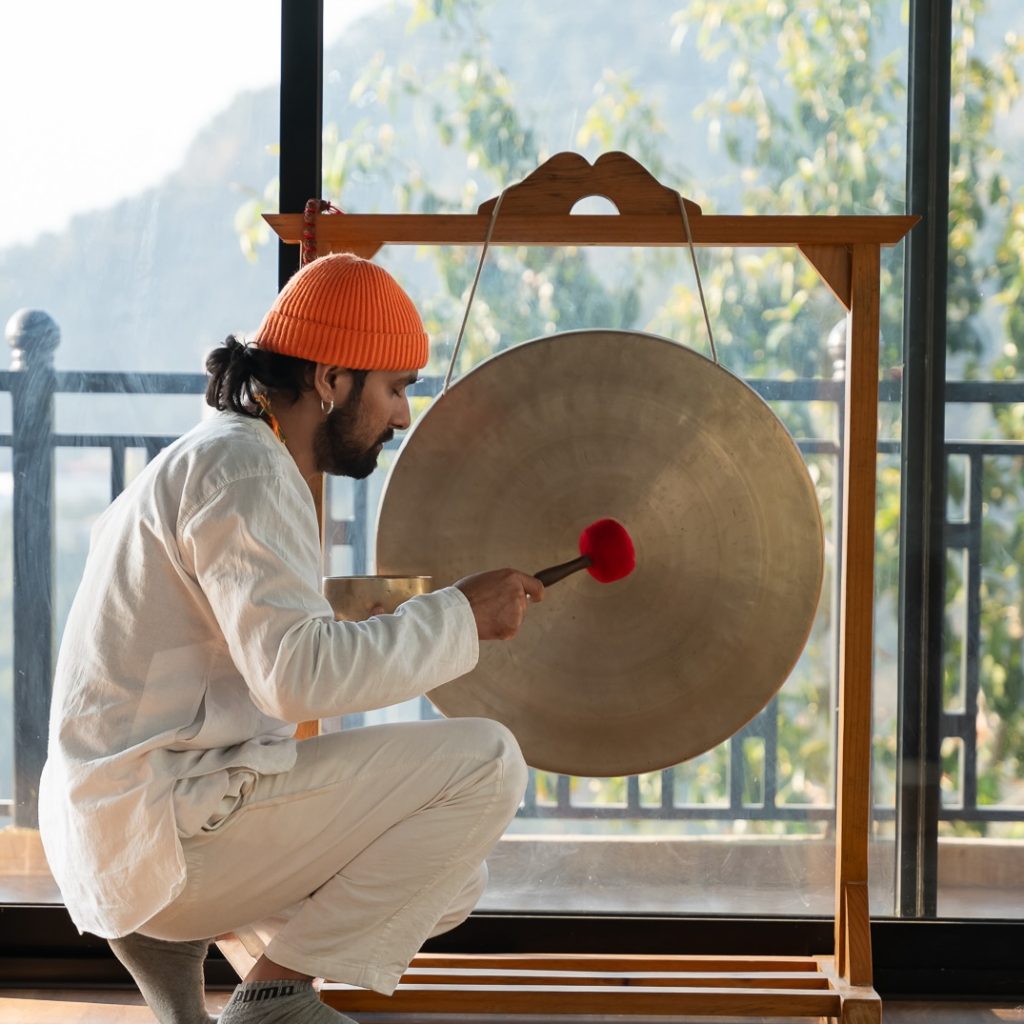 A serene moment of a healer working with a large traditional gong.